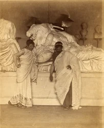 Twee mannelijke studenten in Griekse Kostuum voor een gipsafgietsel van de drie schikgodinnen van de Elgin Marbles, ca. 1882-3